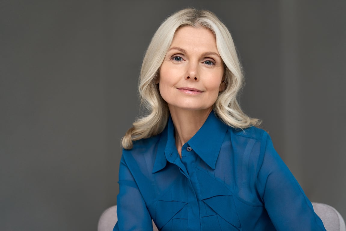 Sophisticated 50S Middle Aged Woman Model Sitting in Chair Looking at Camera.